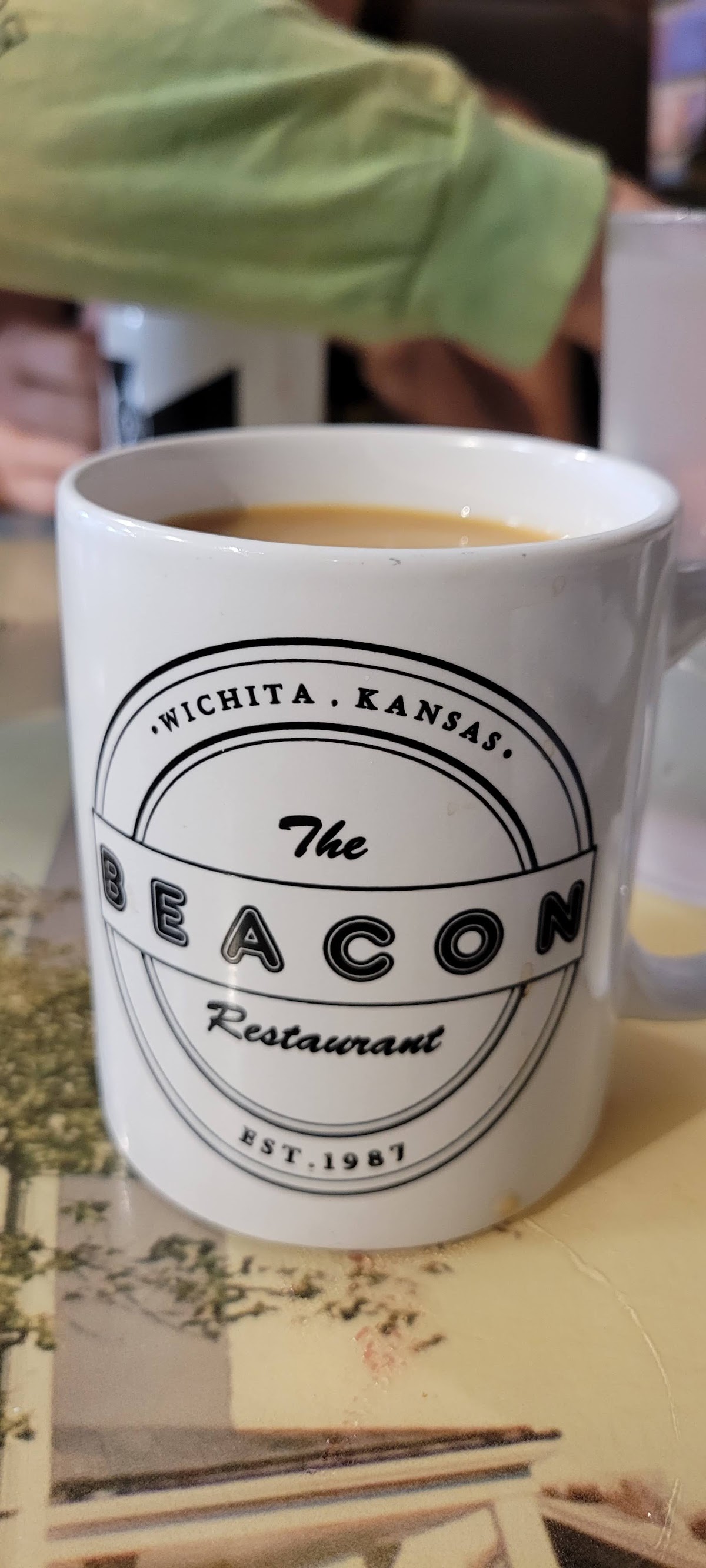 Beacon-branded coffee cup filled with fresh hot coffee